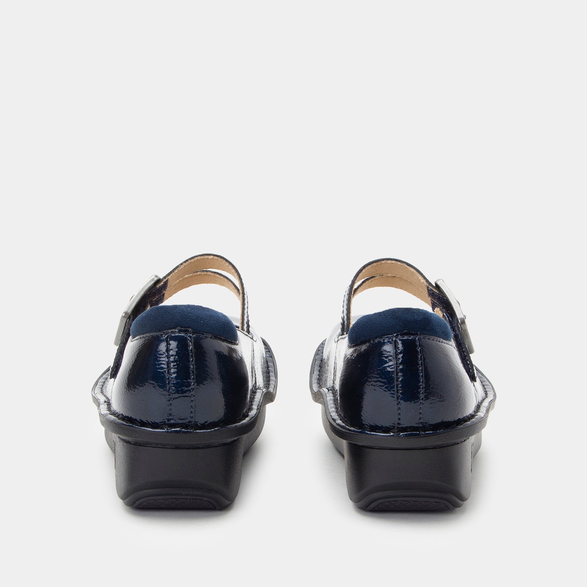 Pair of navy blue shoes with black soles on a light gray background