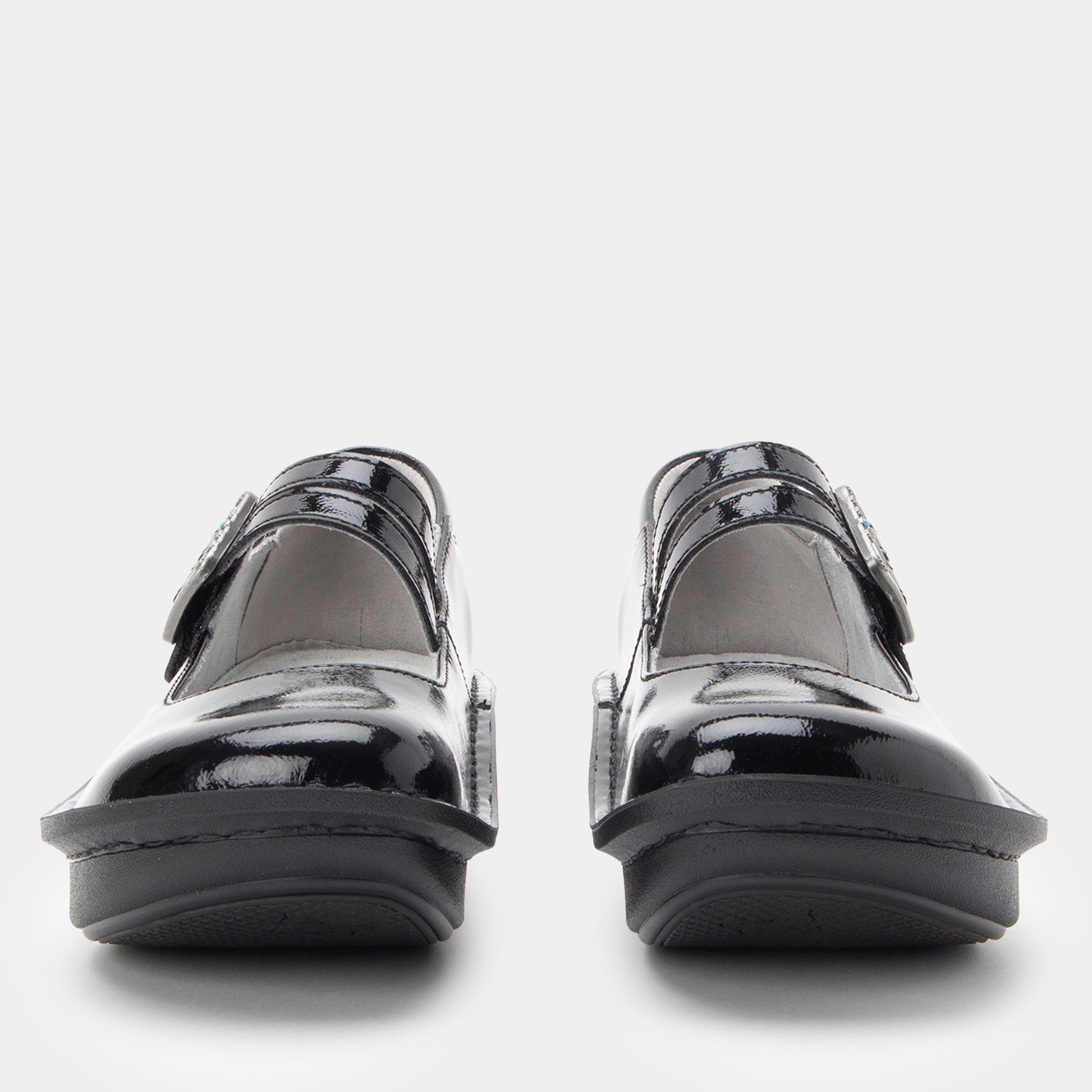 Black patent leather shoes with velcro straps on a white background