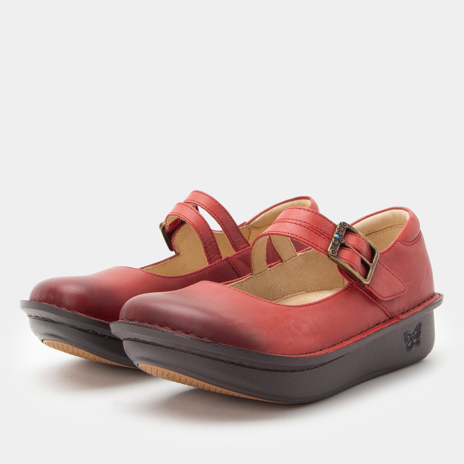 Pair of red shoes with a strap and black sole on a white background