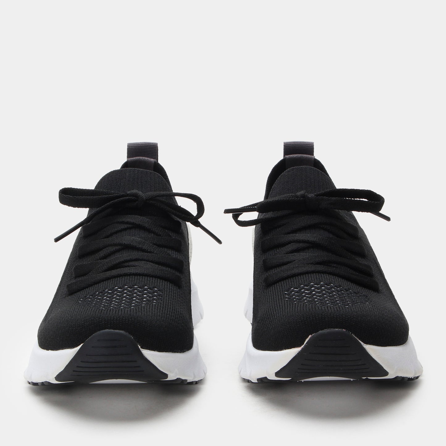 Black athletic shoes with white soles on a light gray background