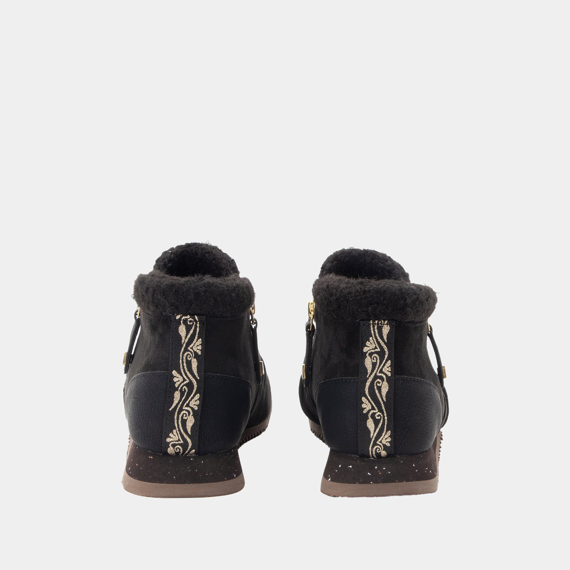 A pair of black ankle boots with shearling trim, featuring vertical gold floral embroidery on the sides and gold-tone hardware, shown from the back against a light gray background.