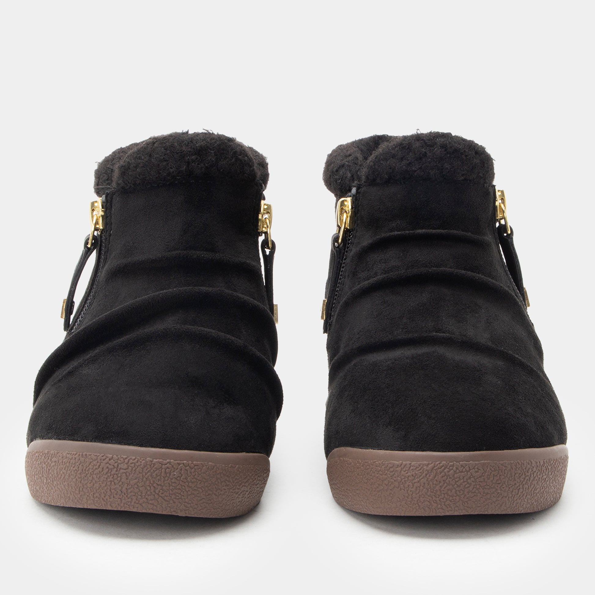 A pair of black suede ankle boots with plush black faux-fur trim at the collar, gold-tone side zippers, and brown textured soles, shown from a front-facing perspective on a light gray background.