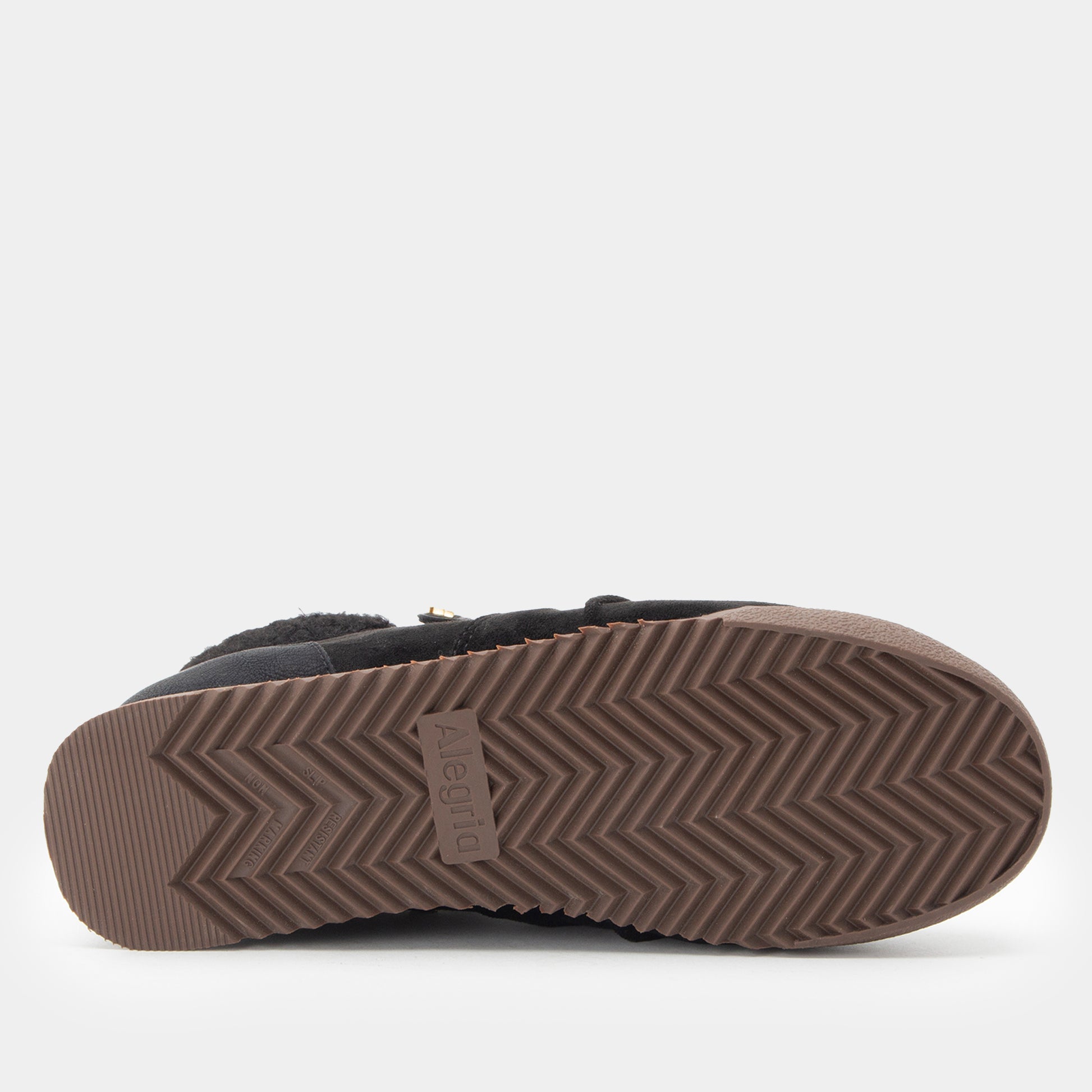 A close-up bottom view of a slipper or boot showing the brown herringbone-patterned outsole with a small 'Alegria' brand tag in the center.