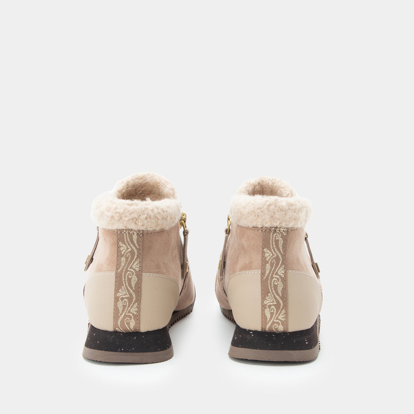 A pair of beige ankle boots with cream shearling lining, decorative vertical floral panels, and dark brown soles, shown from the back on a light gray background.