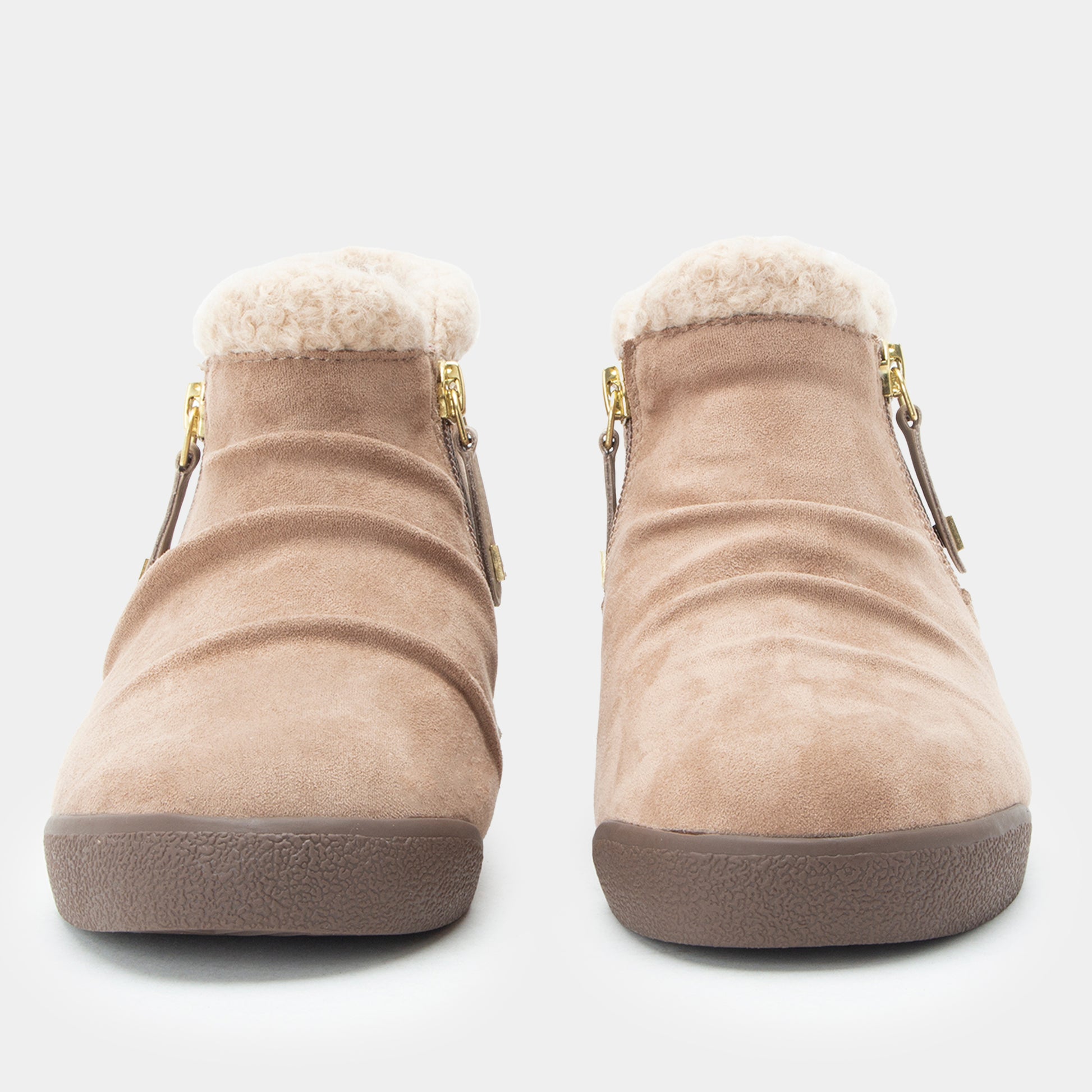A pair of beige suede ankle boots with a soft white shearling lining and gold-tone side zippers, shown from the front on a light gray background.