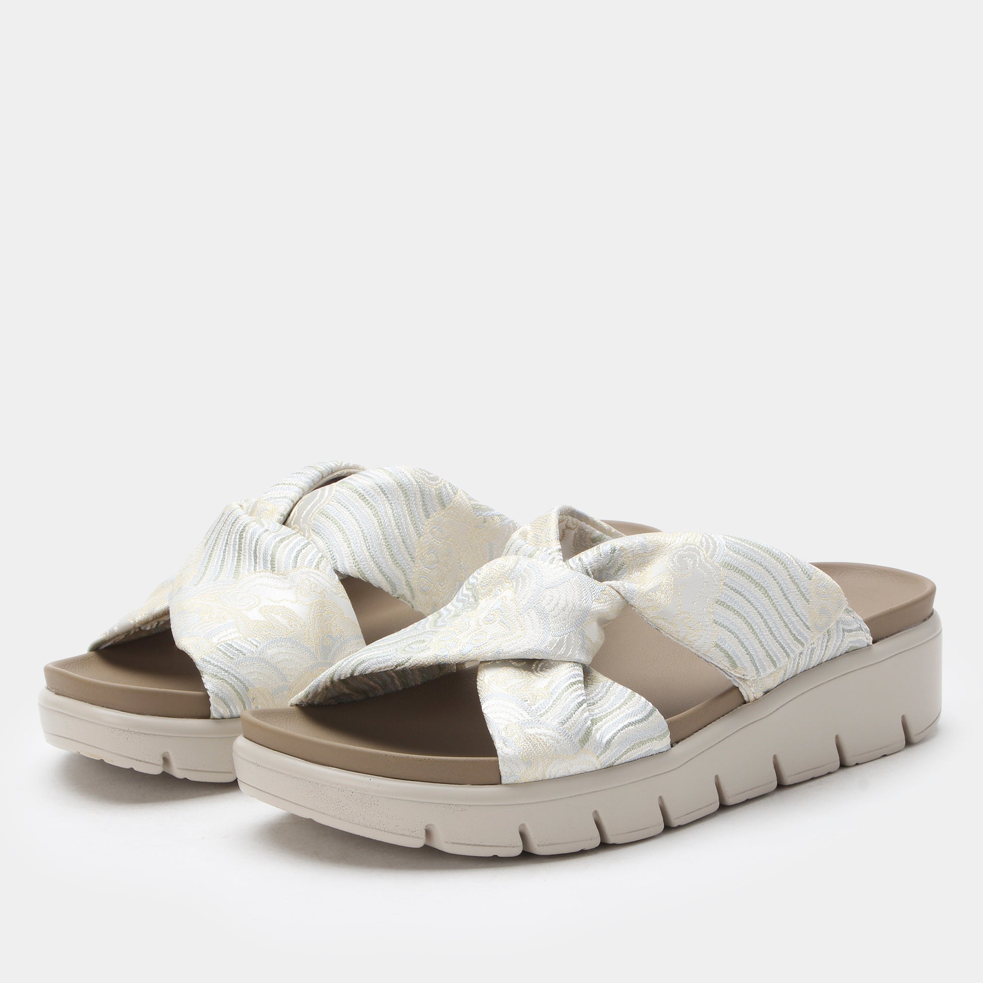 Pair of sandals with a white and brown design on a light gray background