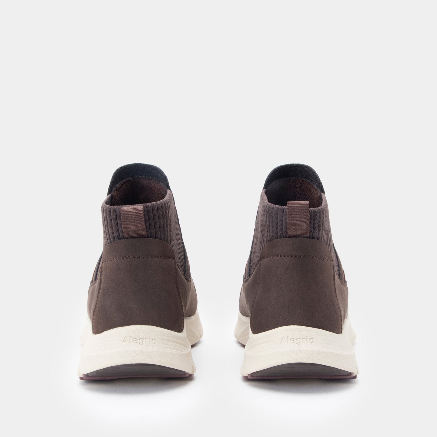 A pair of dark brown ankle-high slip-on sneakers shown from the back, featuring a textured brown upper, elastic side panels, and off-white midsoles with the brand name 'Meglis' printed on them.