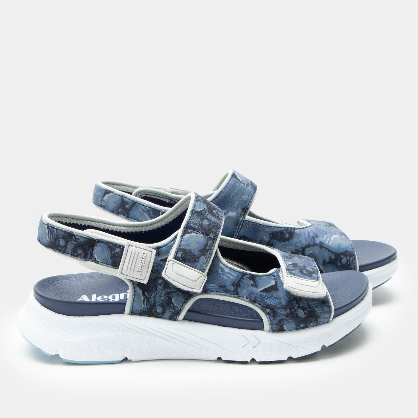 Pair of blue sandals with white soles on a light gray background