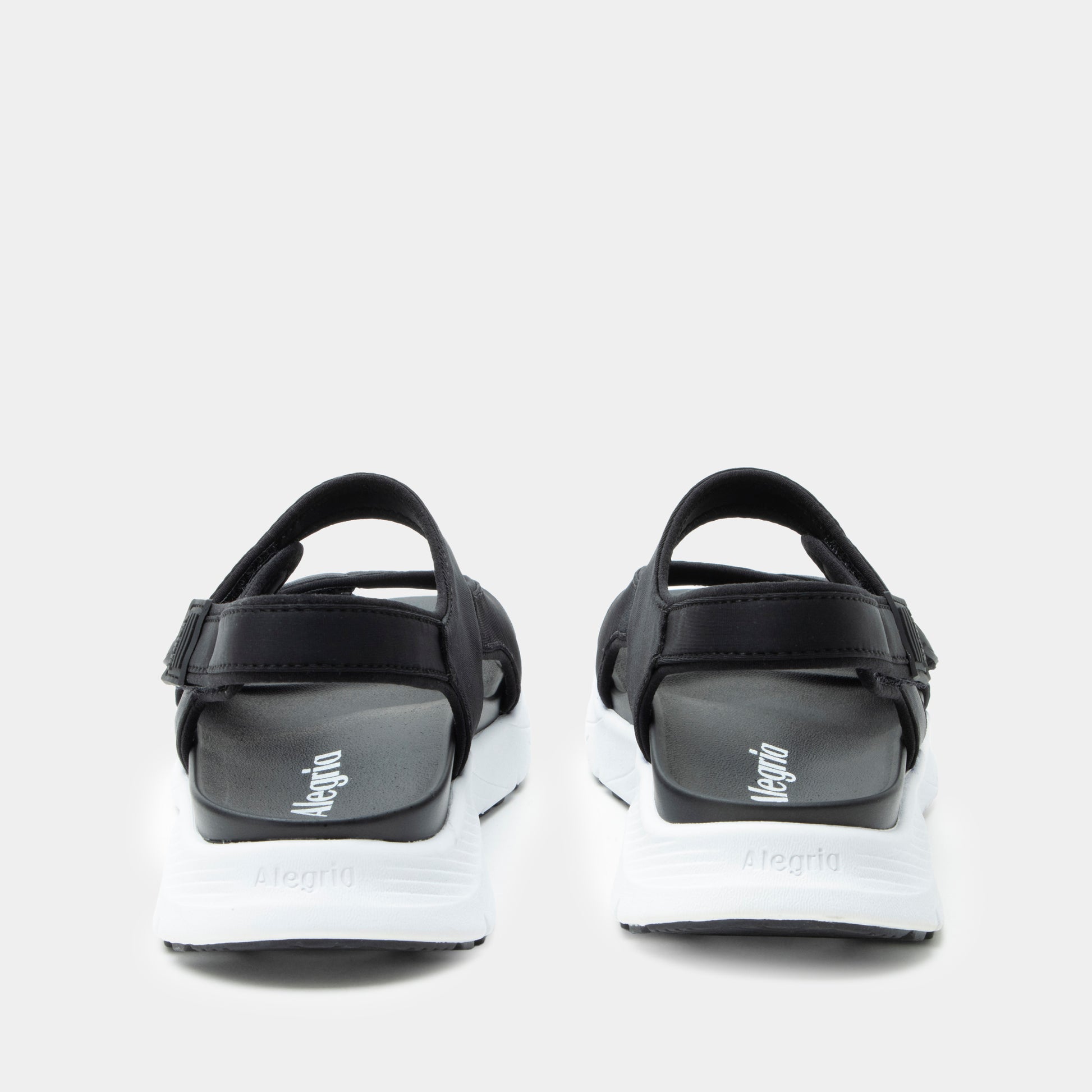 Black and white sandals with 'Megina' branding on a light gray background