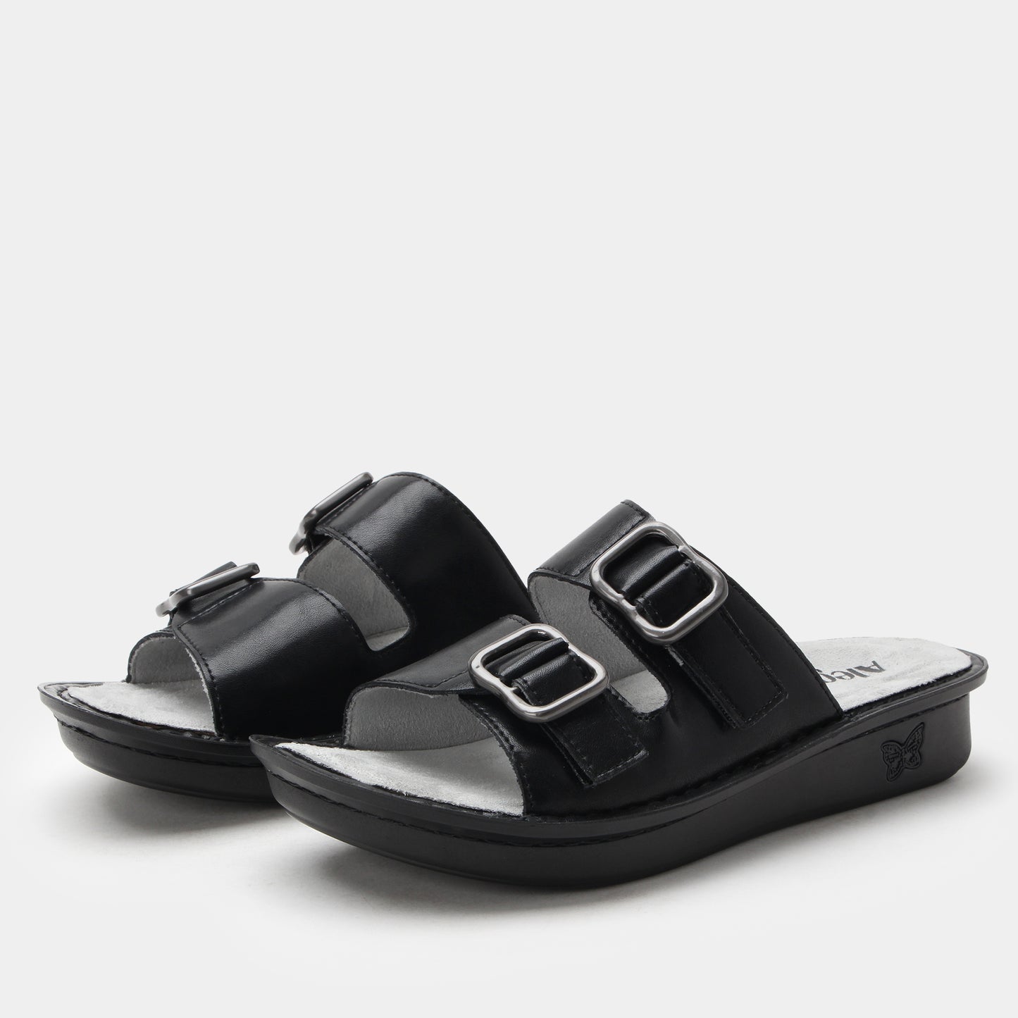 Black sandals with silver buckles on a light gray background