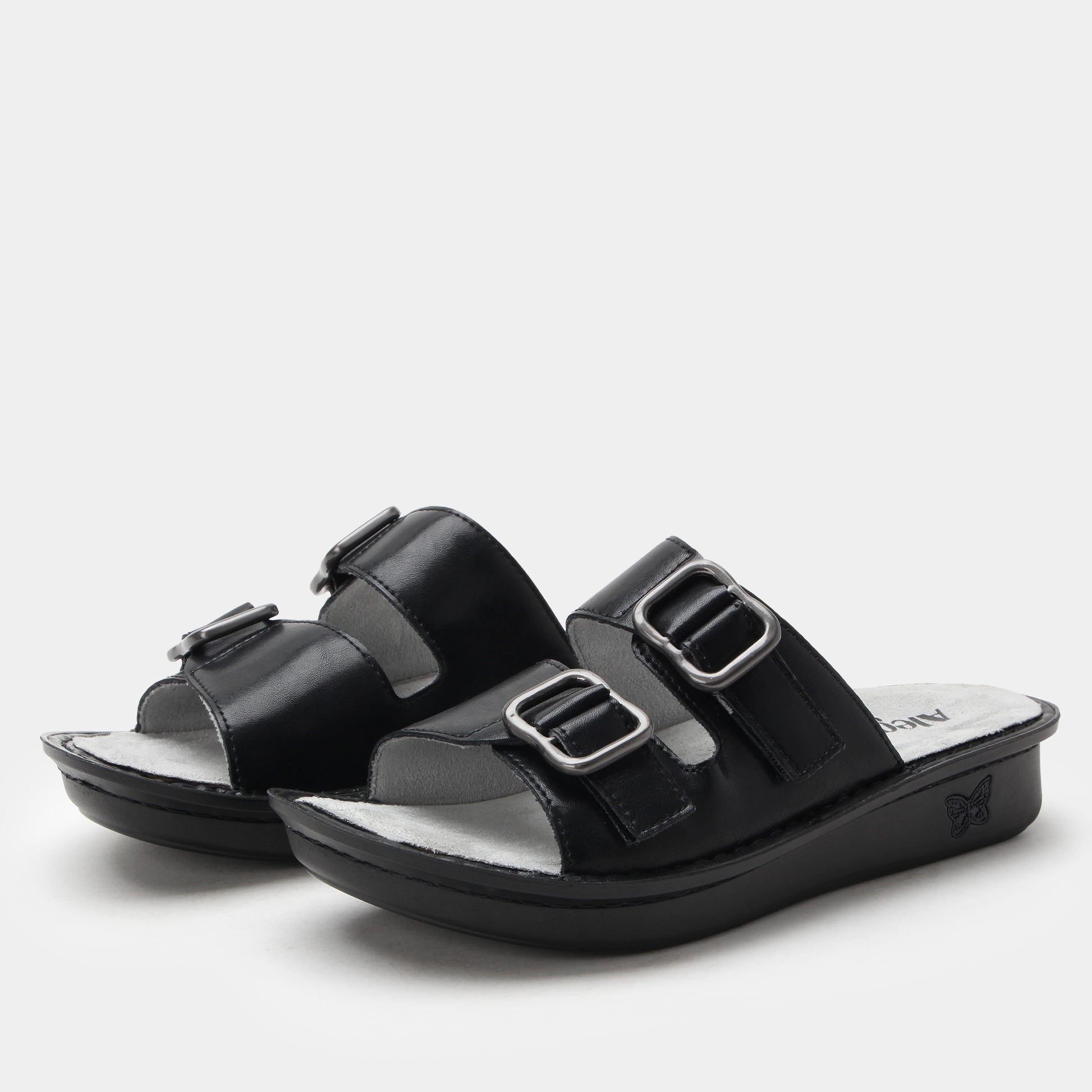 Black sandals with silver buckles on a light gray background