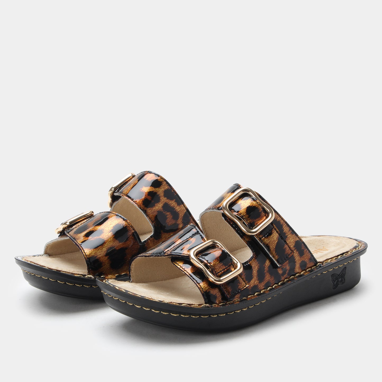 Pair of leopard print sandals with gold buckles on a light gray background