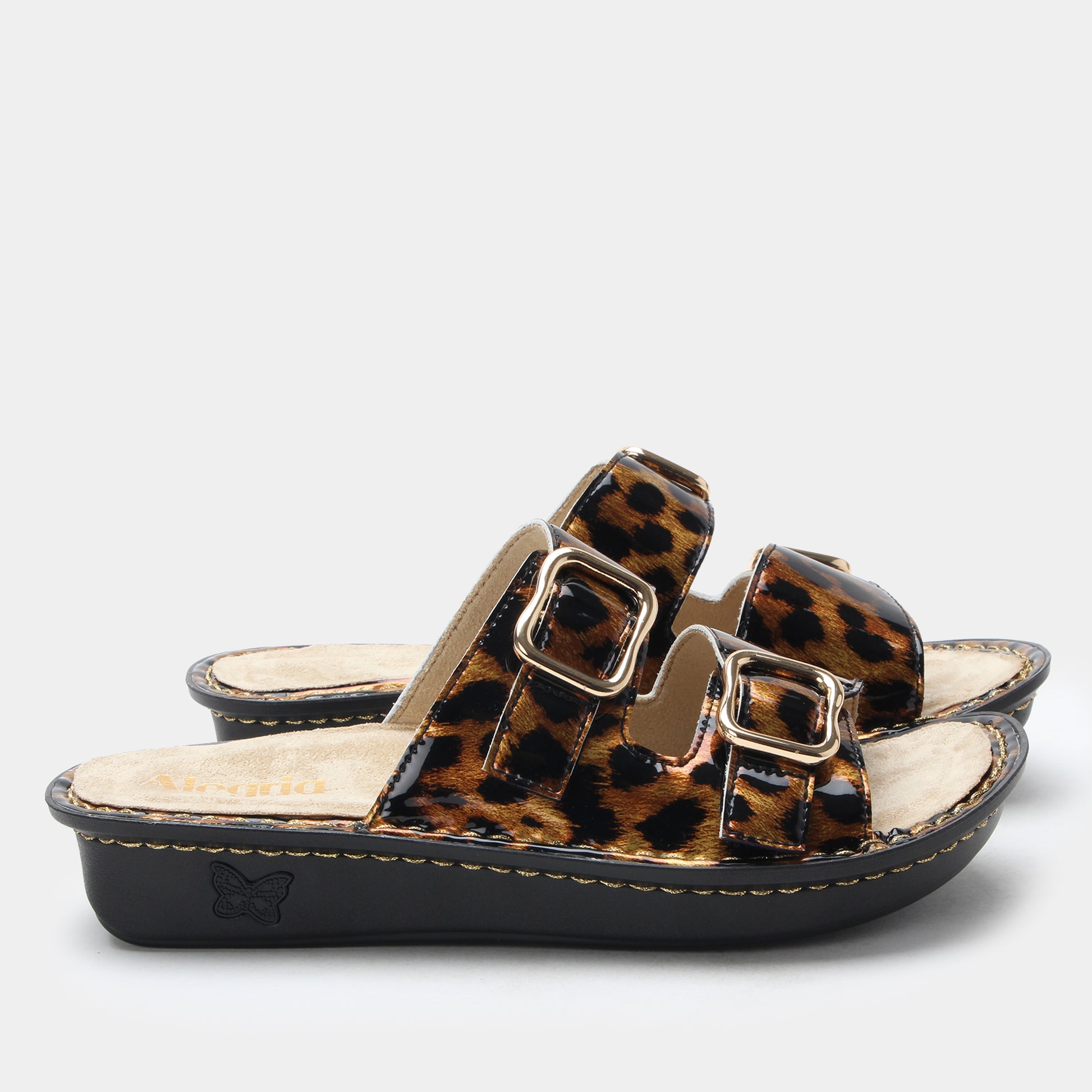 Leopard print sandal with gold buckles on a light gray background