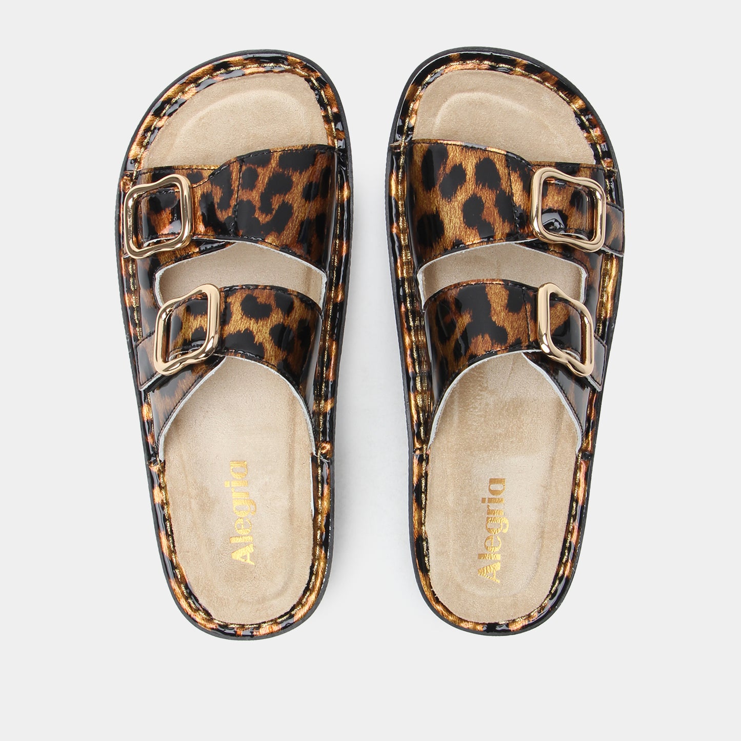 Leopard print sandals with gold buckles on a light gray background