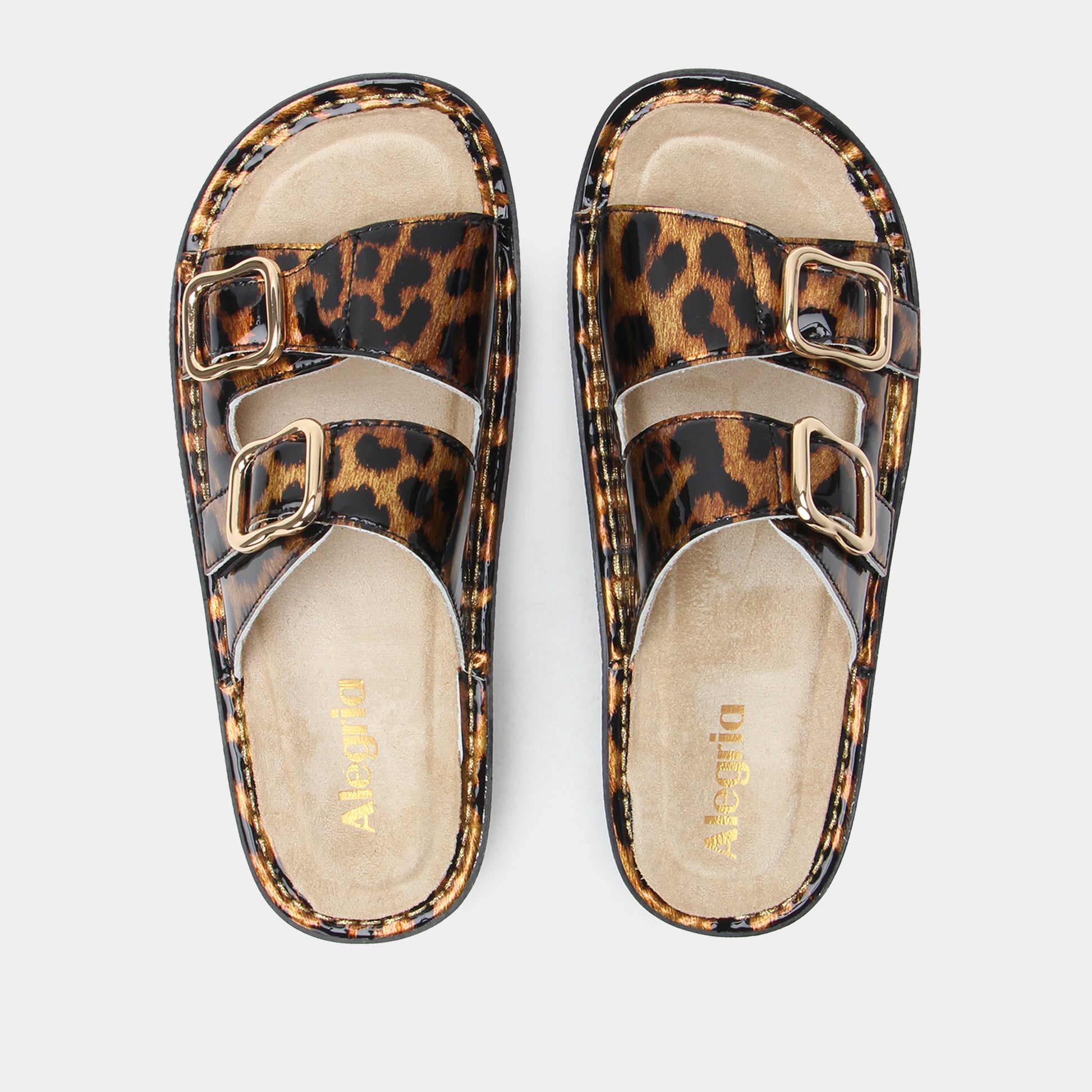 Leopard print sandals with gold buckles on a light gray background