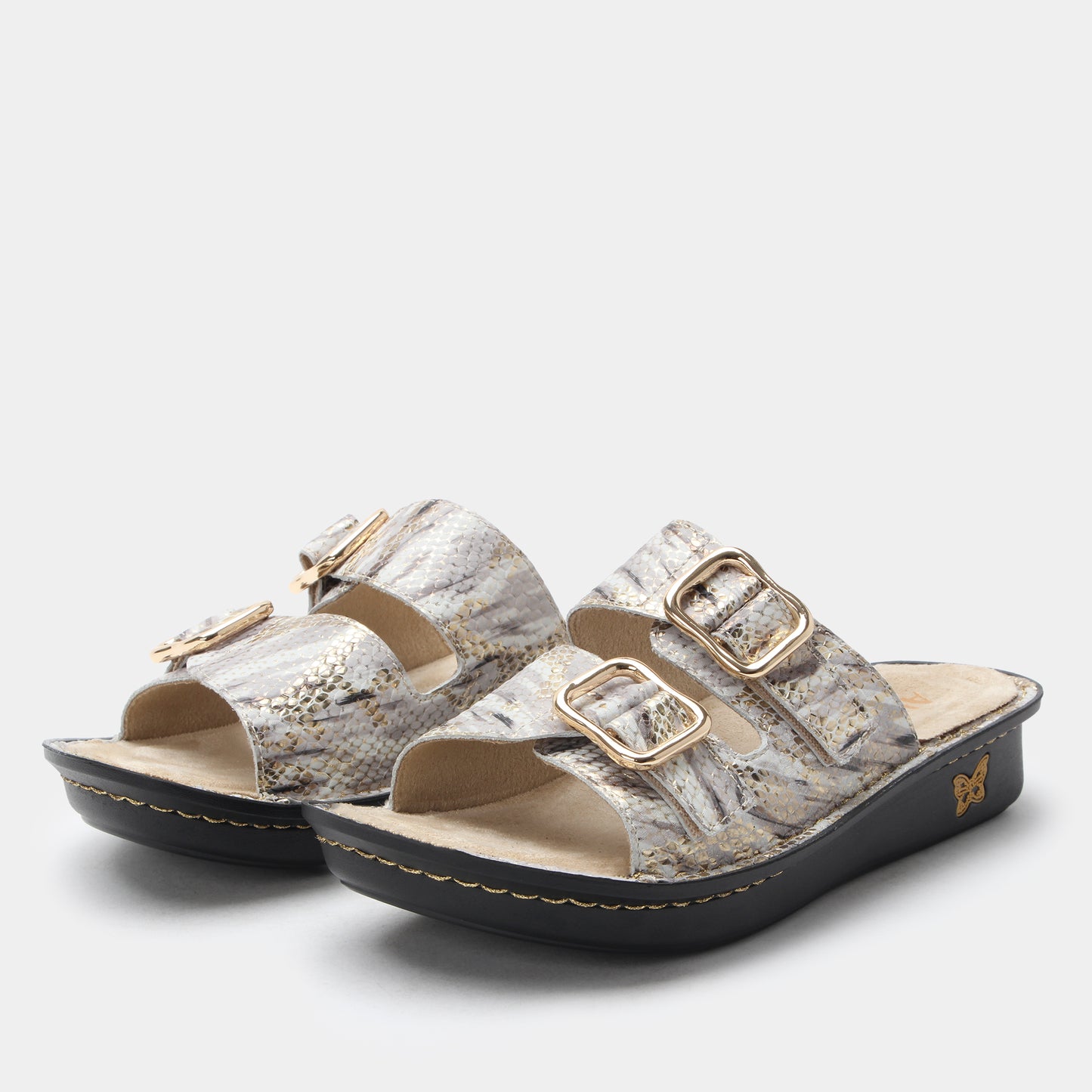 Pair of sandals with gold buckles on a light gray background