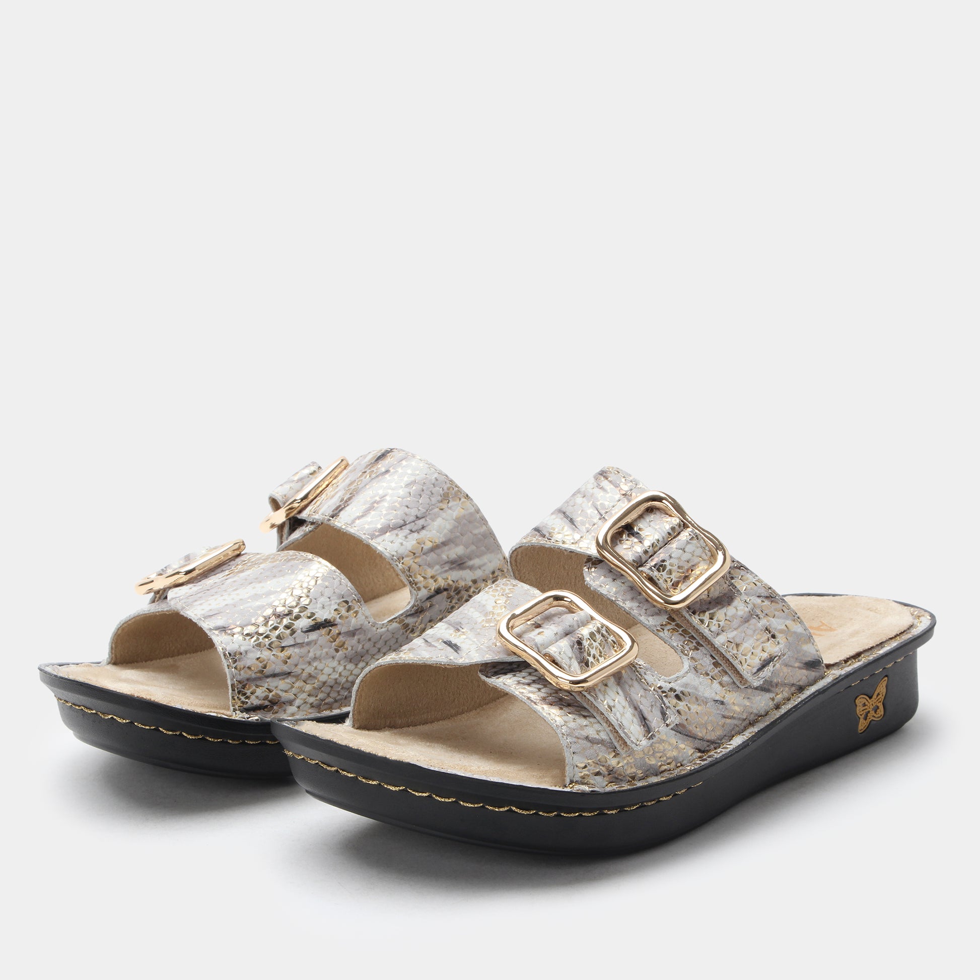 Pair of sandals with gold buckles on a light gray background