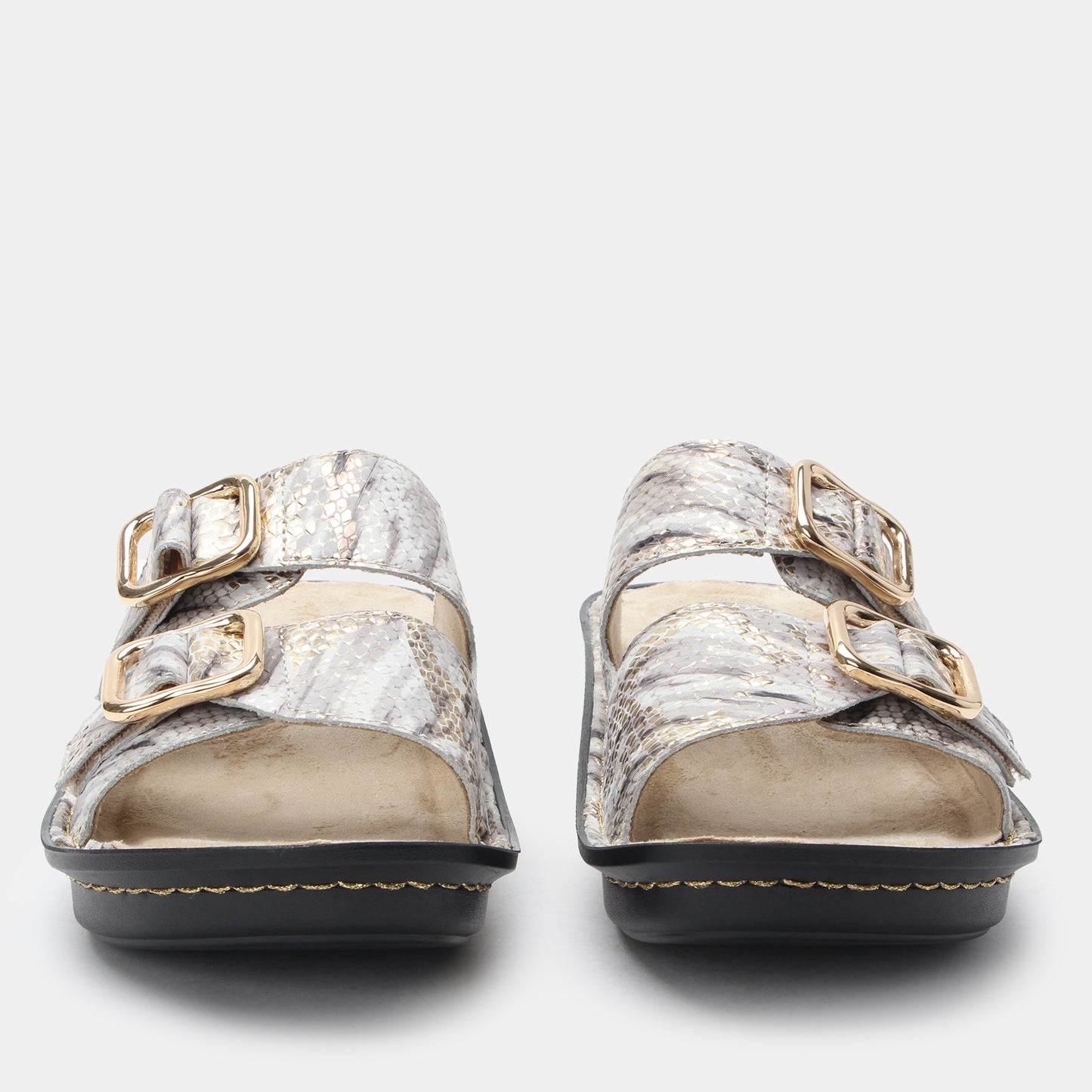Pair of silver sandals with gold buckles on a light gray background