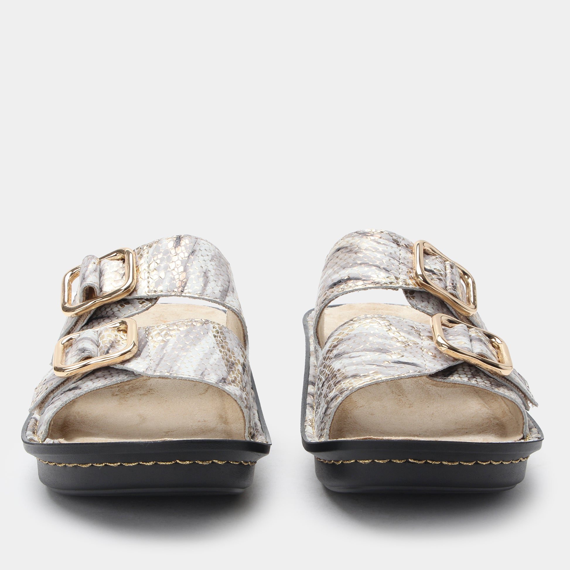 Pair of silver sandals with gold buckles on a light gray background