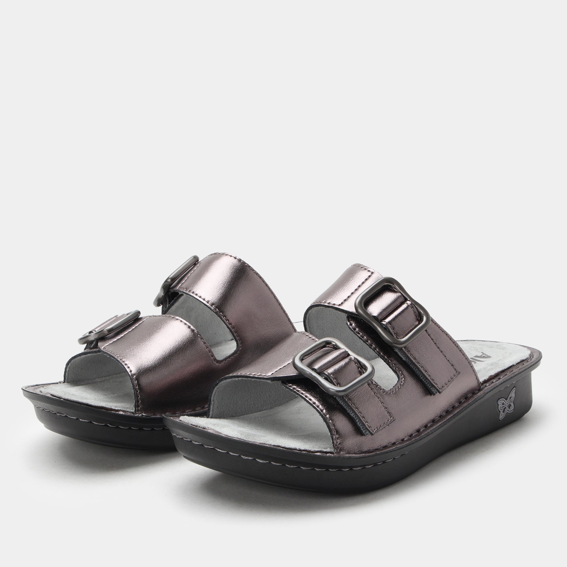 Pair of metallic silver sandals with buckles on a light gray background