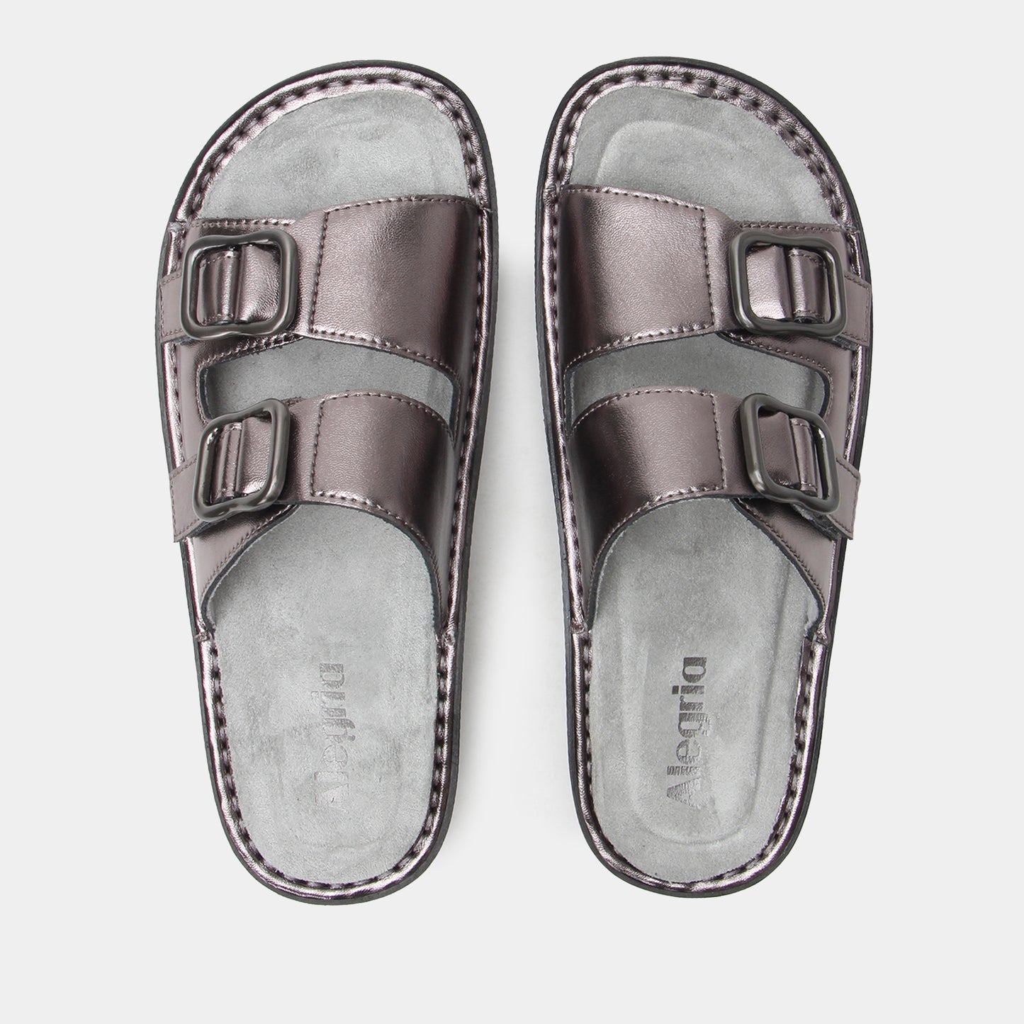 Pair of metallic silver sandals with buckle straps on a light gray background