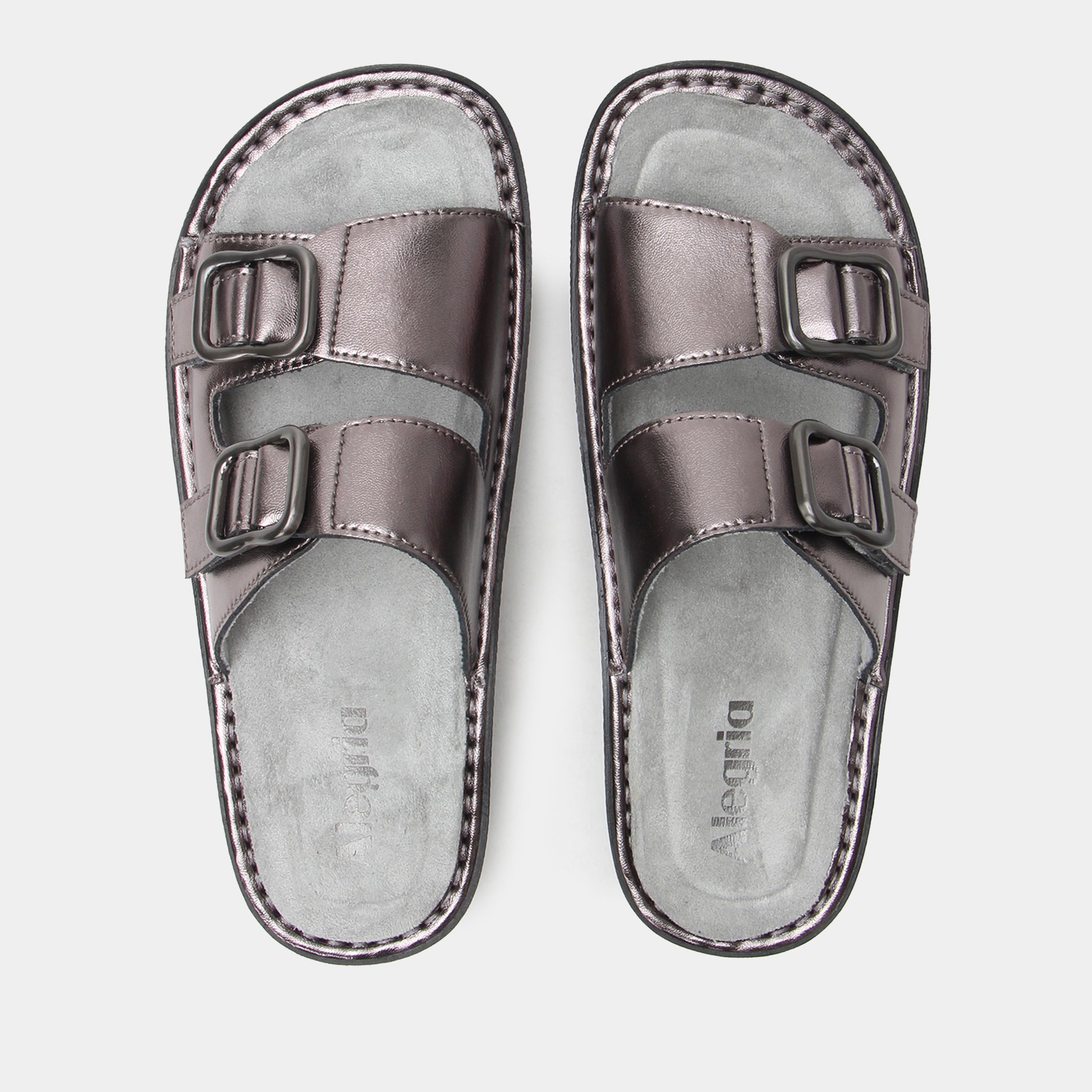 Pair of metallic silver sandals with buckle straps on a light gray background