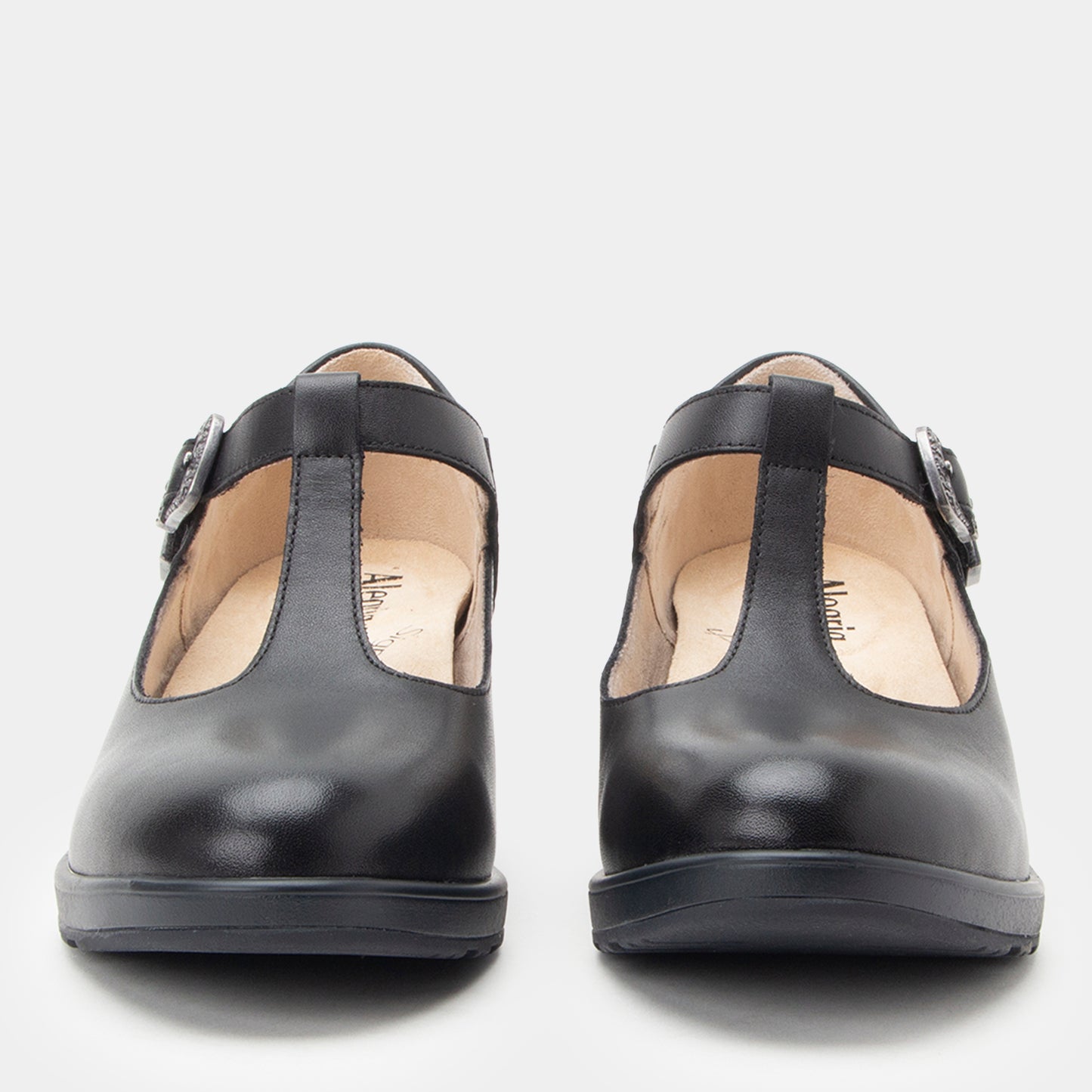 A pair of black leather Mary Jane shoes with adjustable buckle straps, shown from the front on a light gray background.