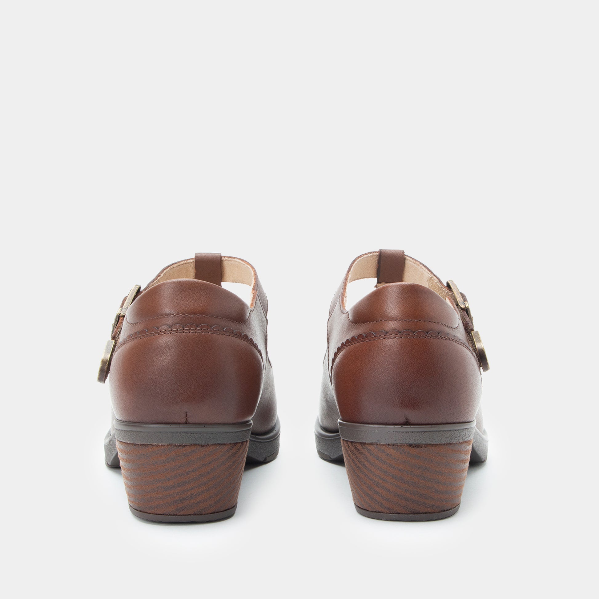 A pair of women's brown leather Mary Jane shoes shown from the back, featuring low stacked block heels and double buckle straps, set against a plain light gray background.
